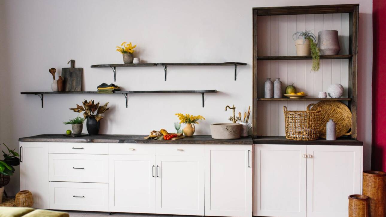 A Scandinavian-style kitchen interior in white and brown tones, featuring a balanced mix of open shelving vs. cabinet with shelves.