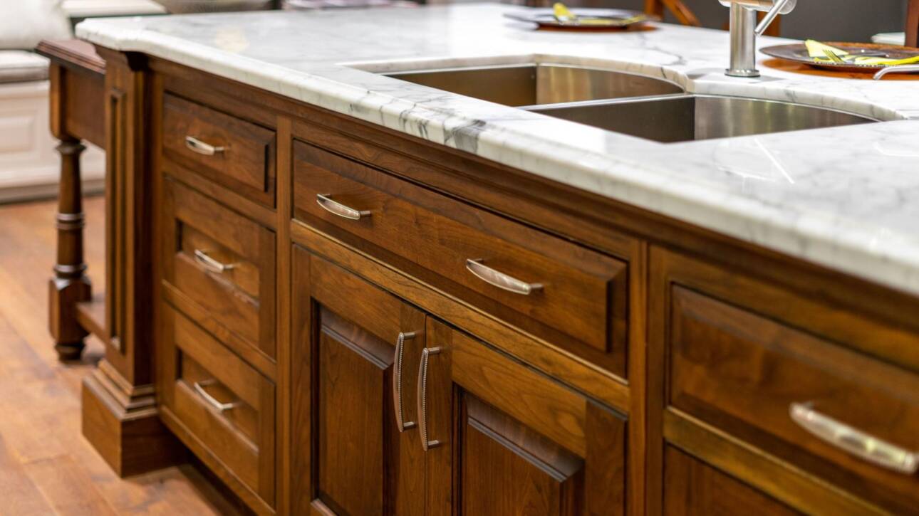 Close-up of a kitchen sink with elegant solid wood cabinets underneath.