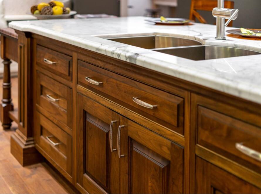 Close-up of a kitchen sink with elegant solid wood cabinets underneath.