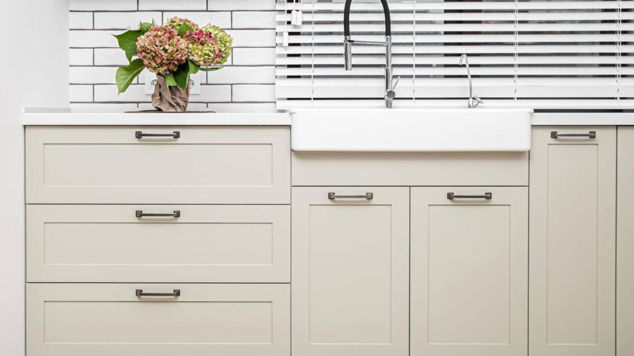 Off-white wooden cabinets in a white kitchen.