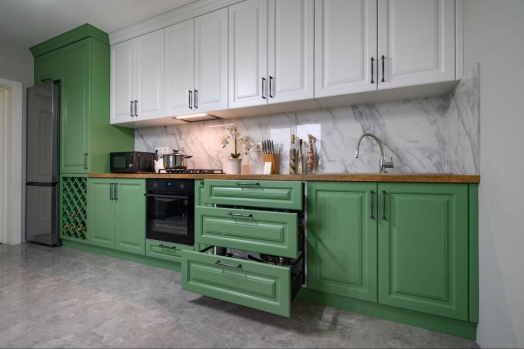 Modern kitchen interior with white and green cabinets in a stylish, well-designed layout.