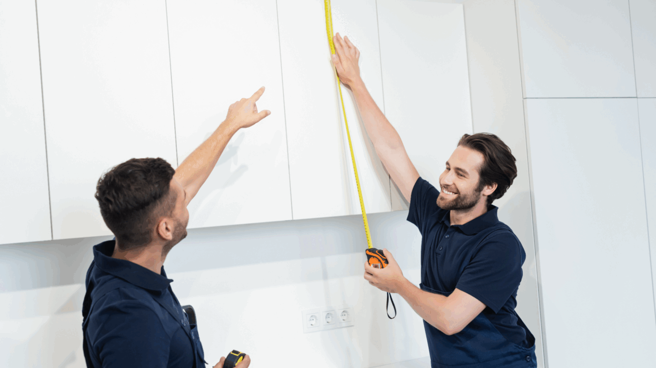 Two workers measuring cabinets.