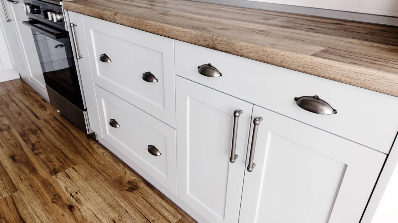 A closeup of Shaker-style cabinets in gray paint with steel handles.