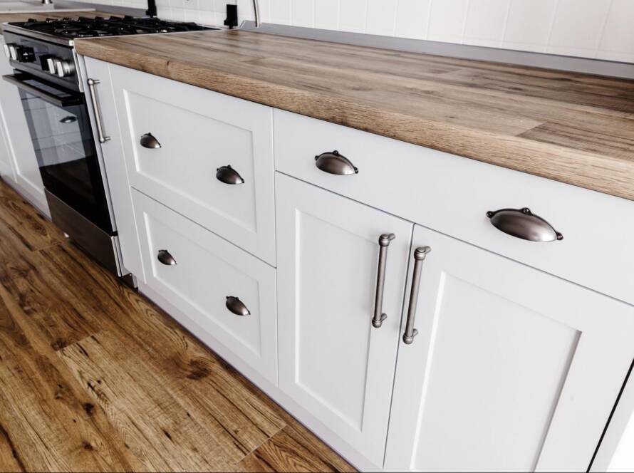 A closeup of Shaker-style cabinets in gray paint with steel handles.