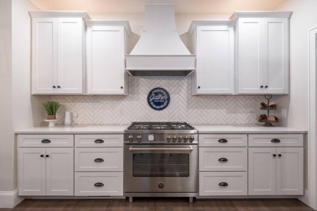 Modern white kitchen cabinets with gas stove and wall-mounted rangehood.