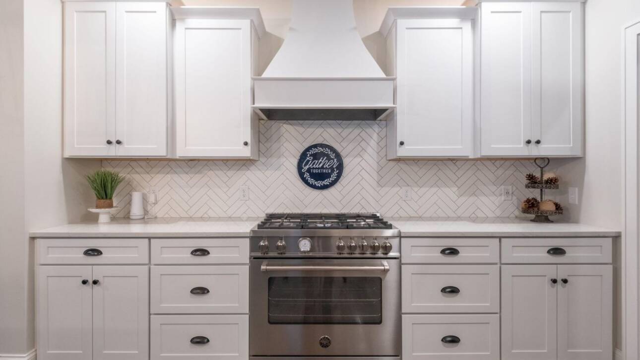 Modern white kitchen cabinets with gas stove and wall-mounted rangehood.