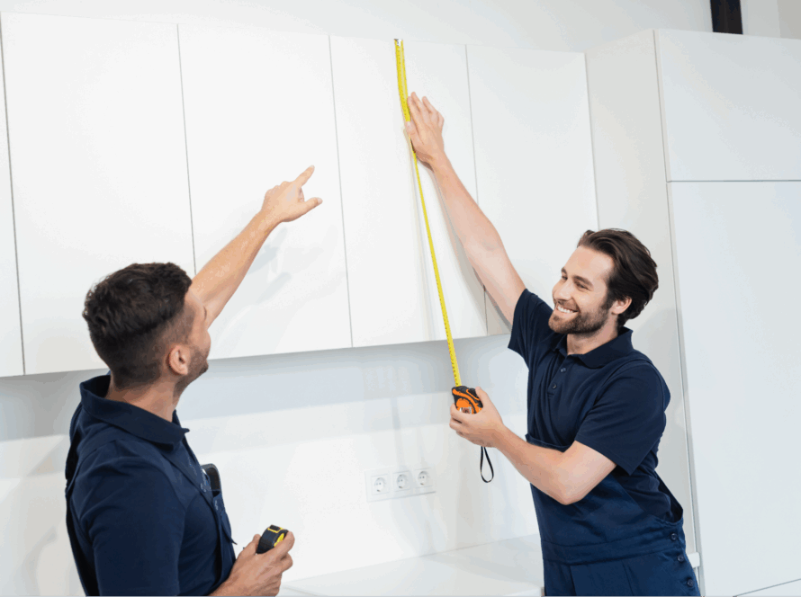 Two workers measuring cabinets.