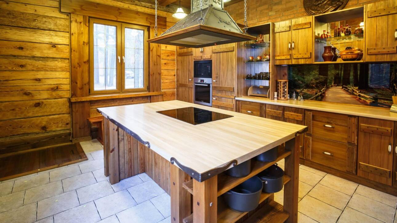 Kitchen interior with natural wood cabinets and a marble-top island with a sink space