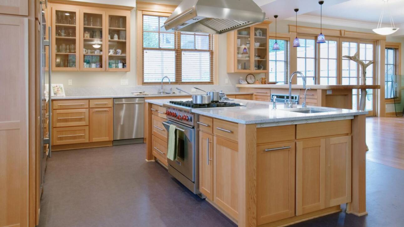 Elegant kitchen interior showcasing custom wooden cabinetry, a spacious center island, and a prominent wooden range hood centerpiece