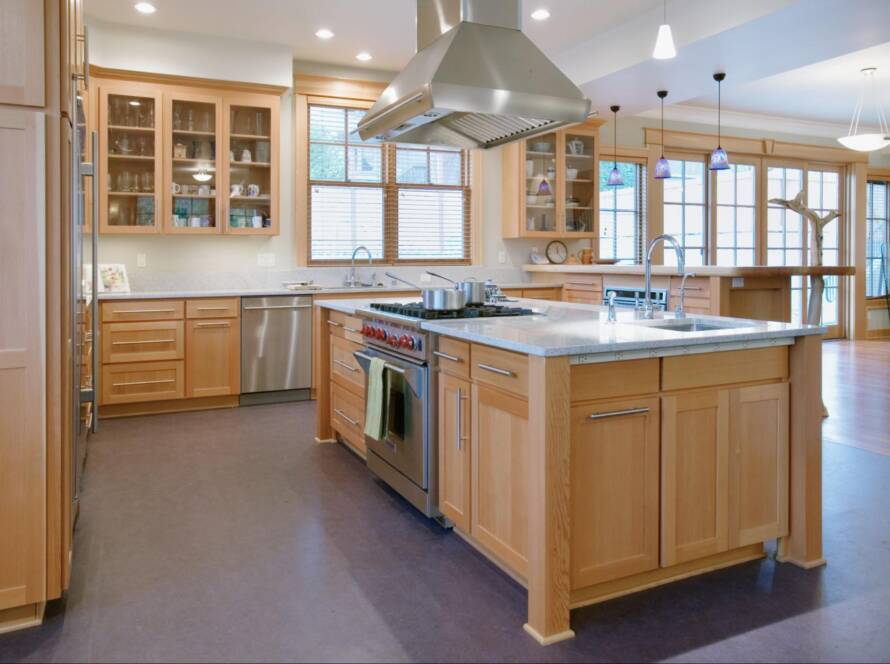 Elegant kitchen interior showcasing custom wooden cabinetry, a spacious center island, and a prominent wooden range hood centerpiece